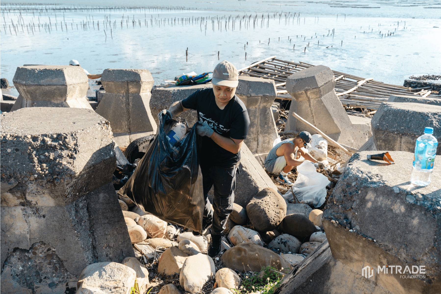 Volunteers collecting marine debris among concrete wave breakers
