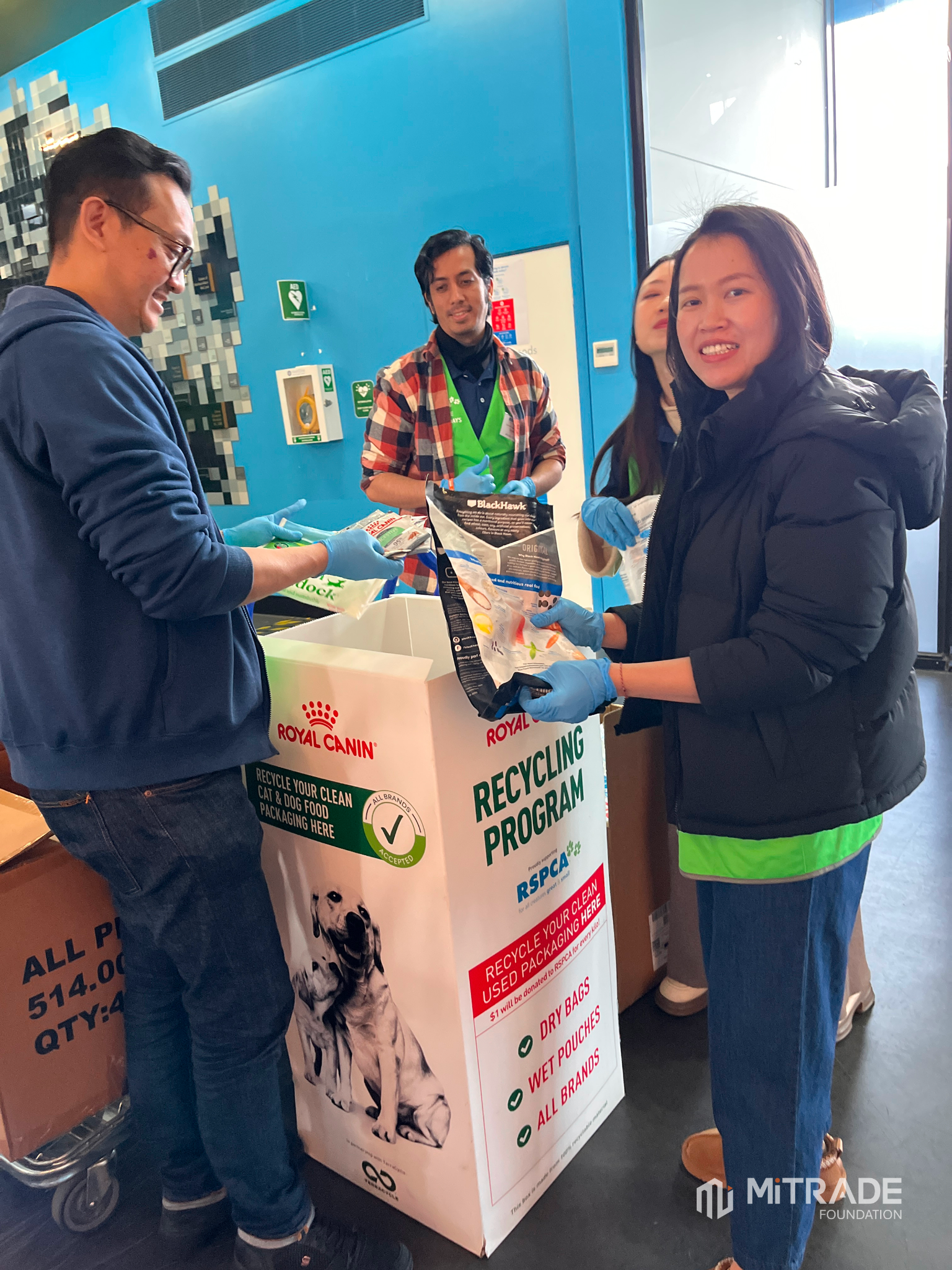 Mitrade volunteers sorting donated recyclable items into an RSPCA collection bin